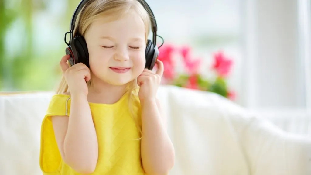 Petite fille pleine d'émotions écoute avec un casque une voix off femme